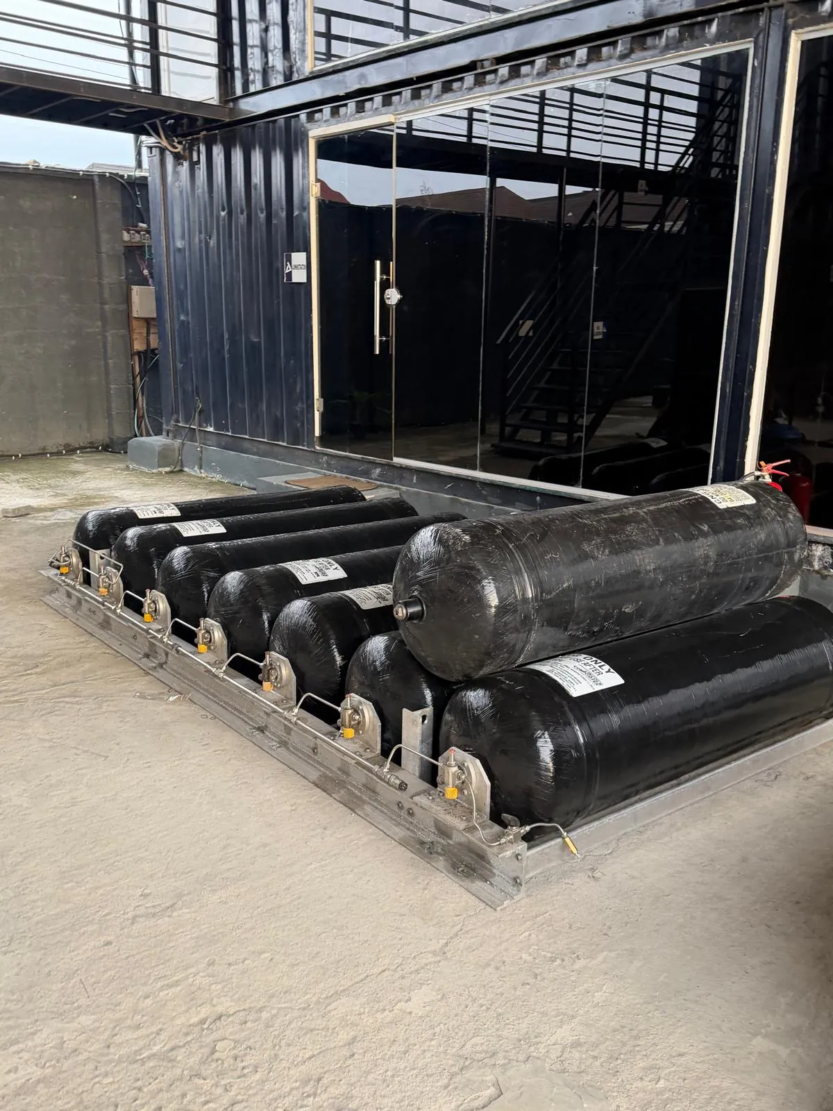 Composite gas cylinders staged beside a TEN-branded container